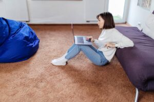 a1interested-woman-works-laptop-computer-sitting-floor-near-black-sofa-min_wp